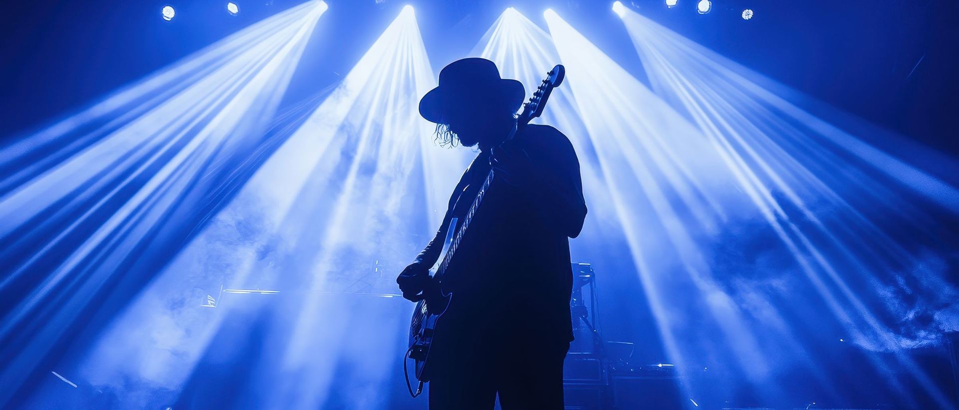 Guitarrista em silhueta num palco com luzes azuis (imagem ilustrativa)