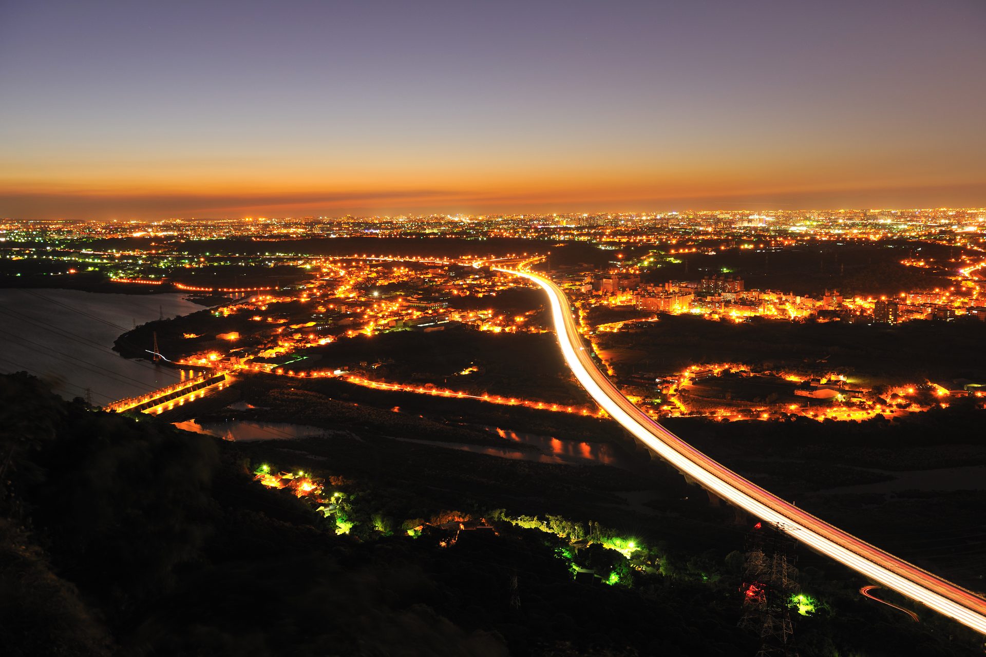 Cidade vista do alto ao anoitecer, com as luzes acesas